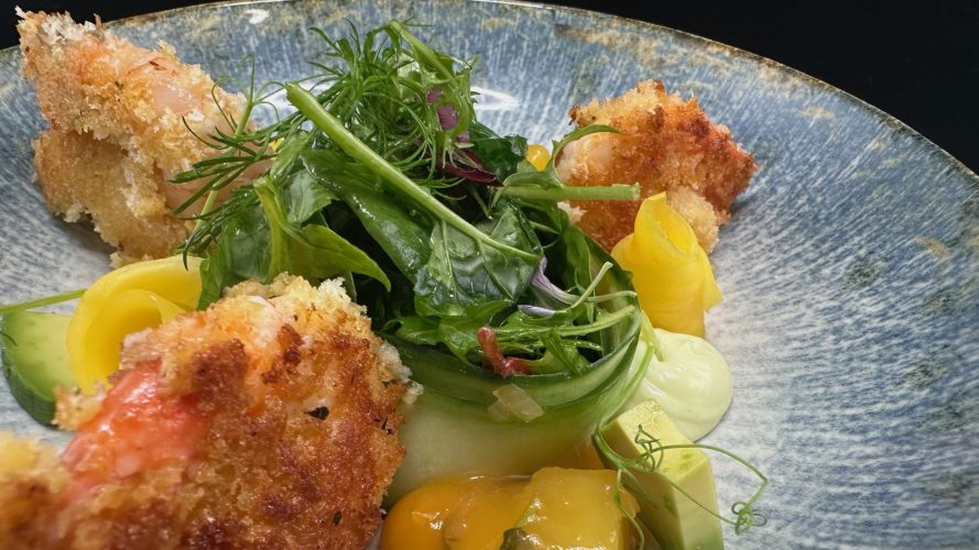 Menuvorschlag: Nahaufnahme von im Teig gebackenen Meeresfrüchten mit bunter Salatdekoration.