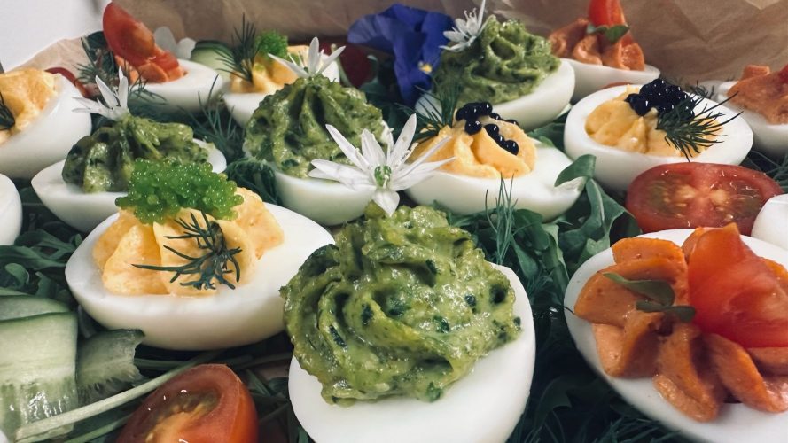 Buffetvorschlag: Mit verschiedenen Pasten gefüllte halbe Eier sind dekoriert mit Tomaten, Gurken und Salat als Vorspeise angerichte.
